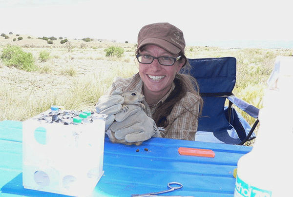 Loren Cassin-Sackett holding a capybara in between her gloved hands while working as Fulbright researcher in Colombia.