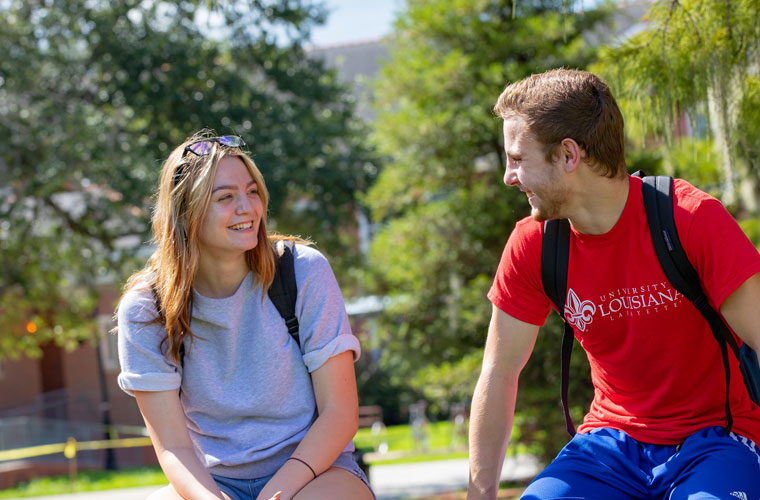 Two University of Louisiana at Lafayette students sitting outside and talking