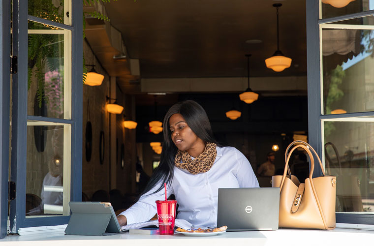 A University of Louisiana at Lafayette student works outside on her computer