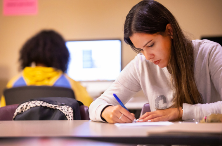 A student writing in a computer lab for communication students on campus.