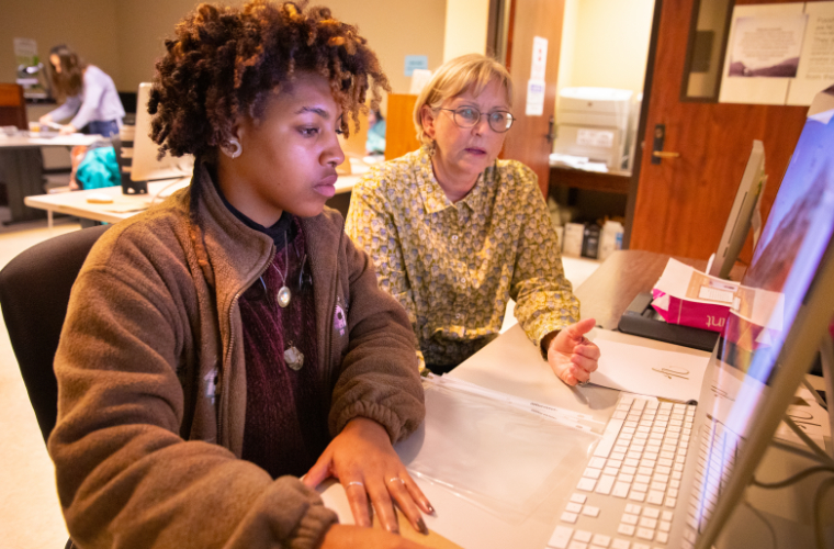 A professor helps a student in a computer lab on campus.