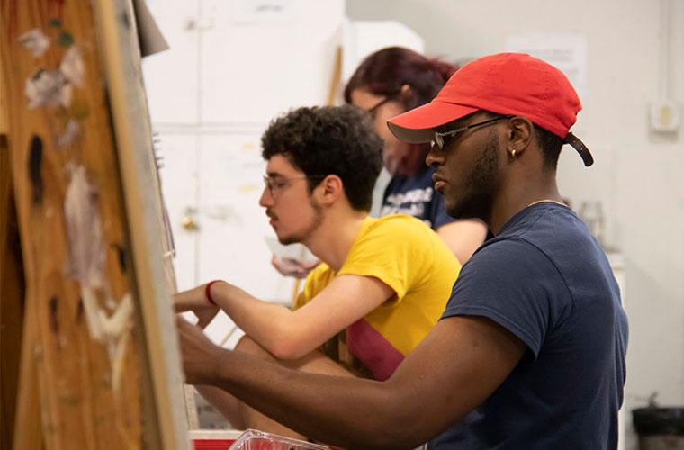 A University of Louisiana at Lafayette painting major sits in front of a canvas and works in the studio
