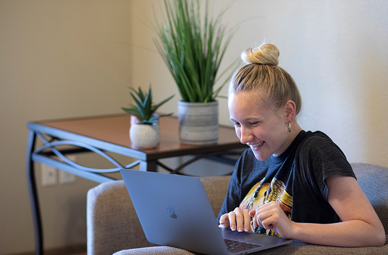 UL Lafayette student using laptop in residence hall wifi