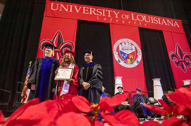 A graduating student receives her diploma at commencement and takes a picture with the college dean