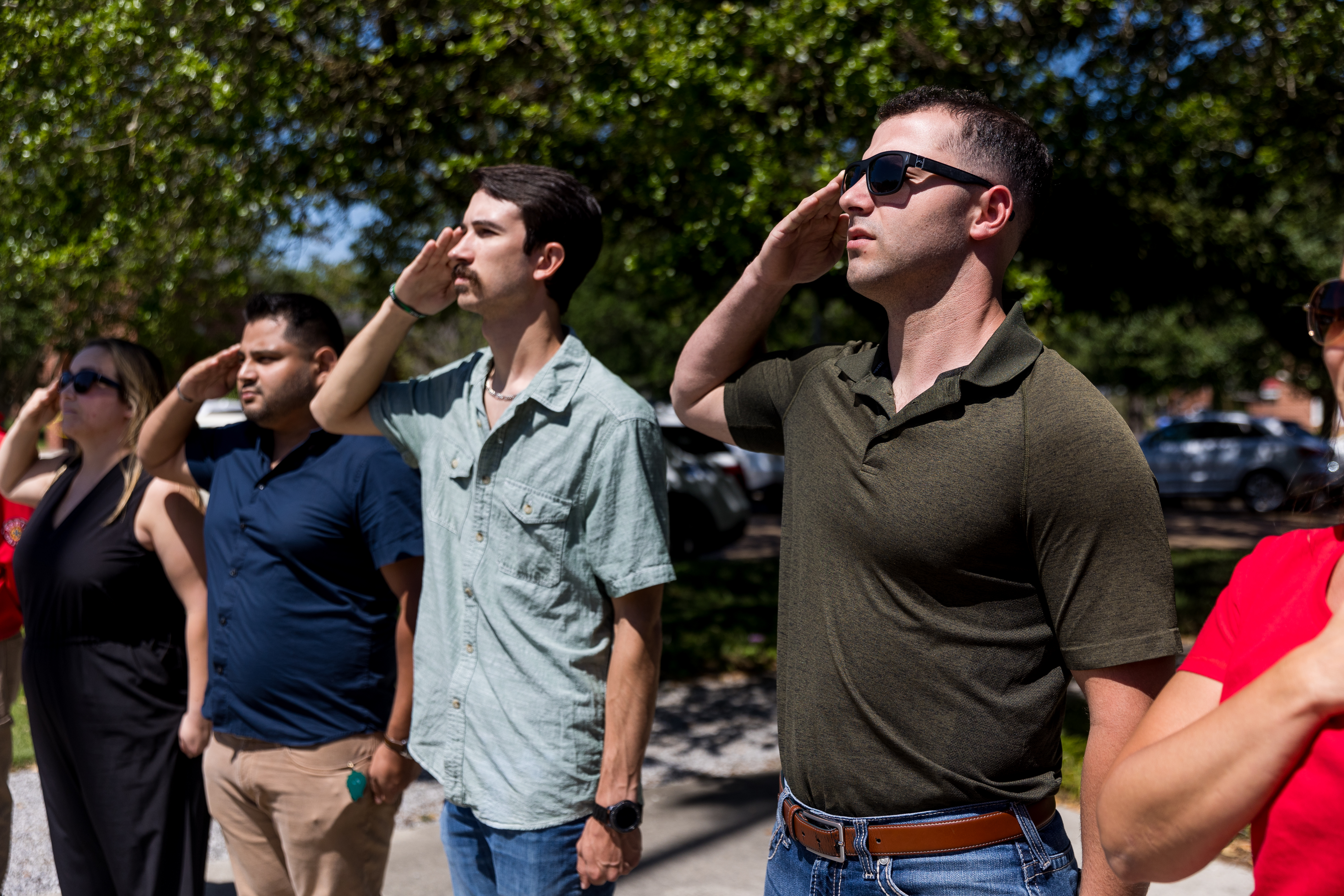 Four students stand saluting to flag