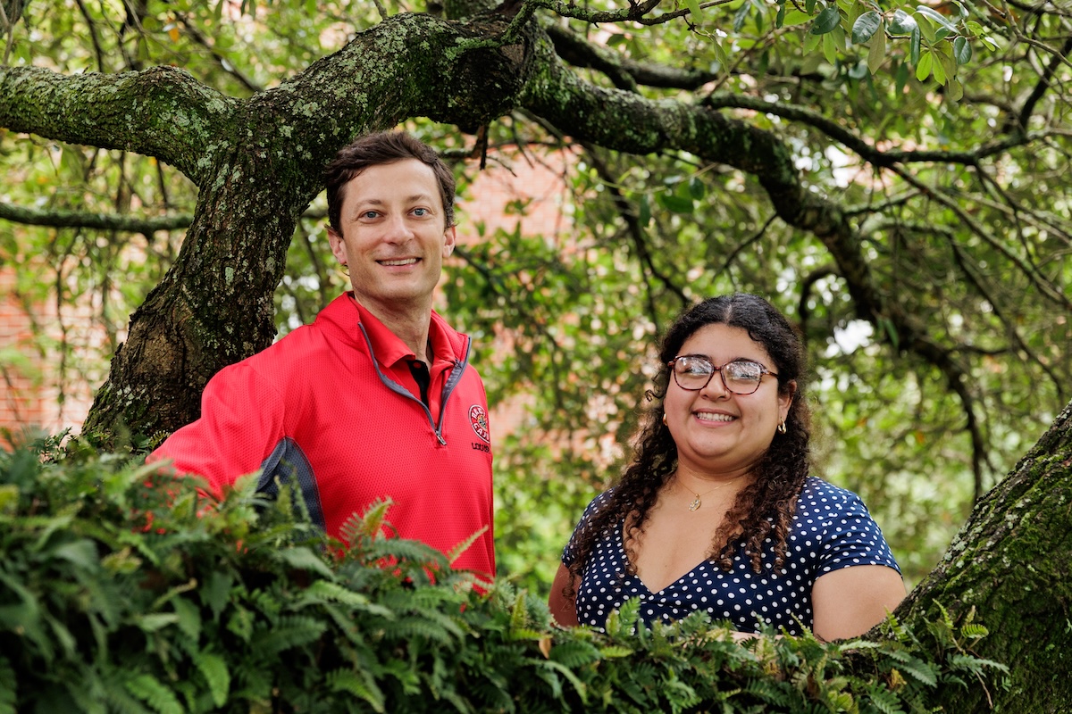 A man and a woman stand among the branches of a large, live oak tree.