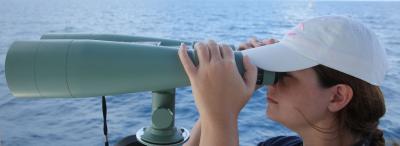 A University of Louisiana at Lafayette research faculty member looks through binoculars over water during a research trip into the Gulf of Mexico