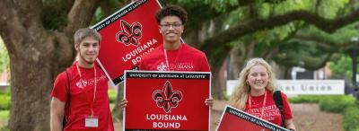 Incoming freshmen hold signs in front of the Student Union
