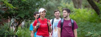 Four University of Louisiana at Lafayette students walk between two rows of gardens on campus