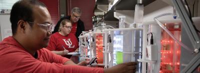 A University of Louisiana at Lafayette researcher working in a lab station while a student and professor take notes