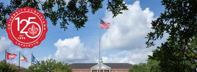 Martin Hall on a bright sunny day, UL Lafayette's 125-year anniversary emblem at the top left