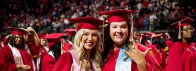 Two students smilling during commencement ceremony