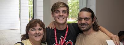 Family members on either side of a student in a black UL shirt and a red UL lanyard.