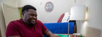 student in dorm room using laptop