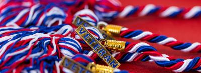 Red, white, and blue graduation tassels with gold charms that say "VETERAN"