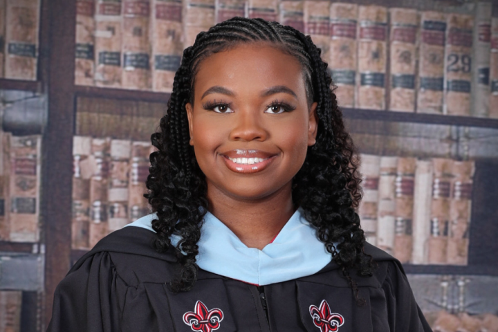 Masters in Gifted Education graduate smiles for portrait in black UL Lafayette master's regelia. 