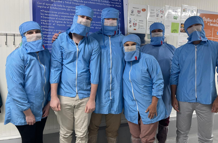 MBA students wear blue protective gear while touring a food production facility in Costa Rica.
