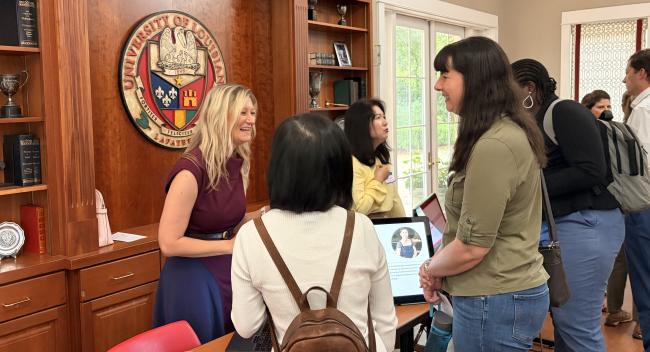 Three women are pictured around a table presentation during the 2026 FLC Showcase.